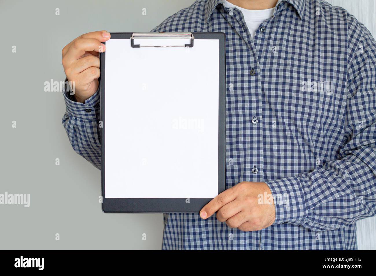 Man holding clipboard with white blank paper sheet Stock Photo - Alamy