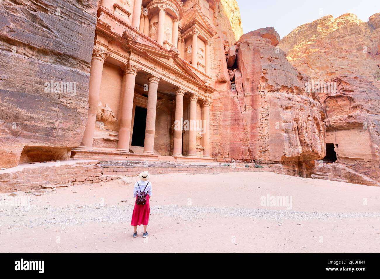 young girl traveler with hat standing on viewpoint in Petra ancient city looking at the Treasury or Al-khazneh, famous travel destination of Jordan an Stock Photo