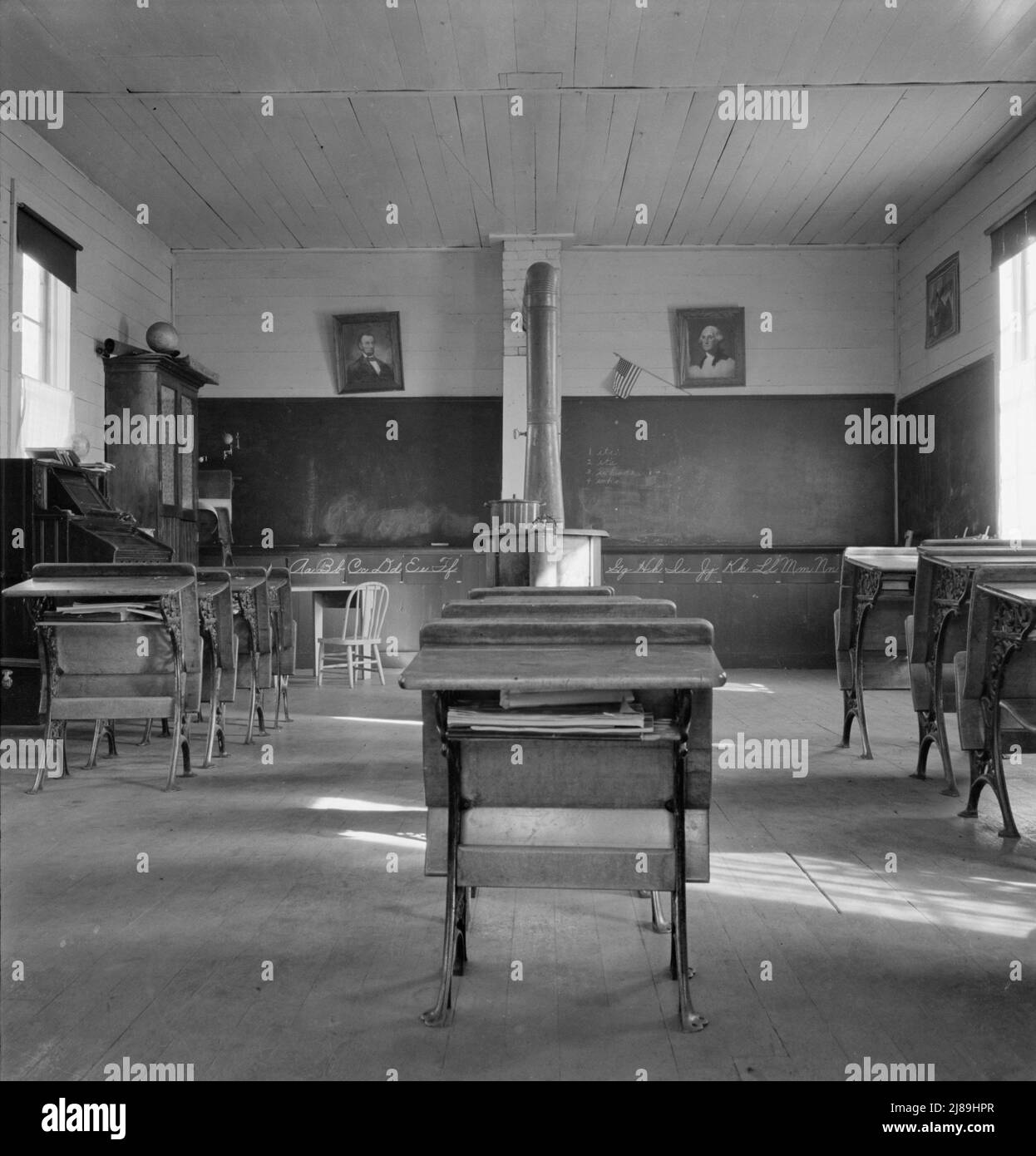 Interior of eastern Oregon one-room county school. Seven pupils enrolled. 8:45 a.m. Between Pleasant Valley and Durkee, Baker County, Oregon. [Note stove for heating, and portraits of George Washington and Abraham Lincoln]. Stock Photo