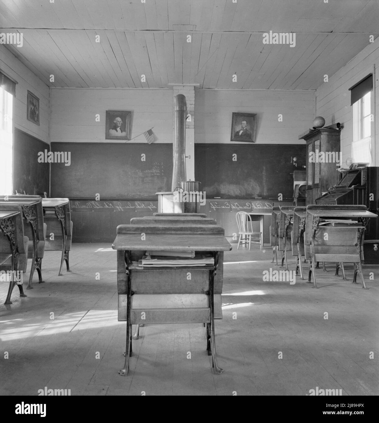 Interior of eastern Oregon one-room county school. Seven pupils enrolled. 8:45 a.m. Between Pleasant Valley and Durkee, Baker County, Oregon. [Note stove for heating, and portraits of George Washington and Abraham Lincoln]. Stock Photo