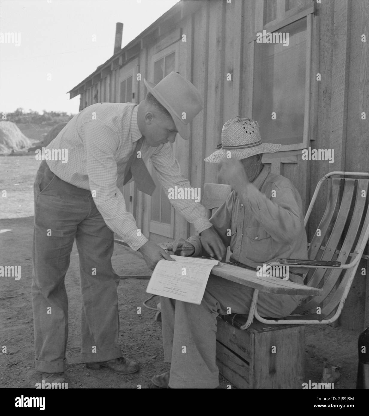 Oklahoma farmer, now living in Cow Hollow, is a FSA (Farm Security Administration) borrower. Seen here signing his chattel mortgage. Malheur County, Oregon. [FSA official with Mr. Sam Cates]. Stock Photo