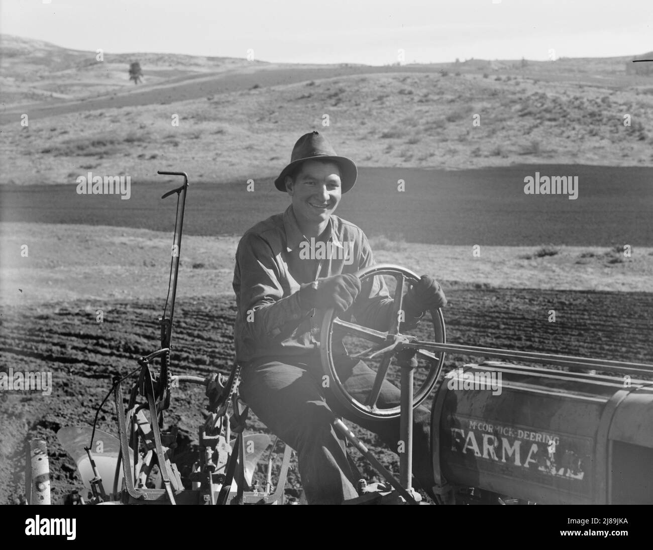 Young farmer, member of Ola self-help sawmill co-op, plowing in fall of the year. Tractor is used co-operatively. Gem County, Idaho. Stock Photo