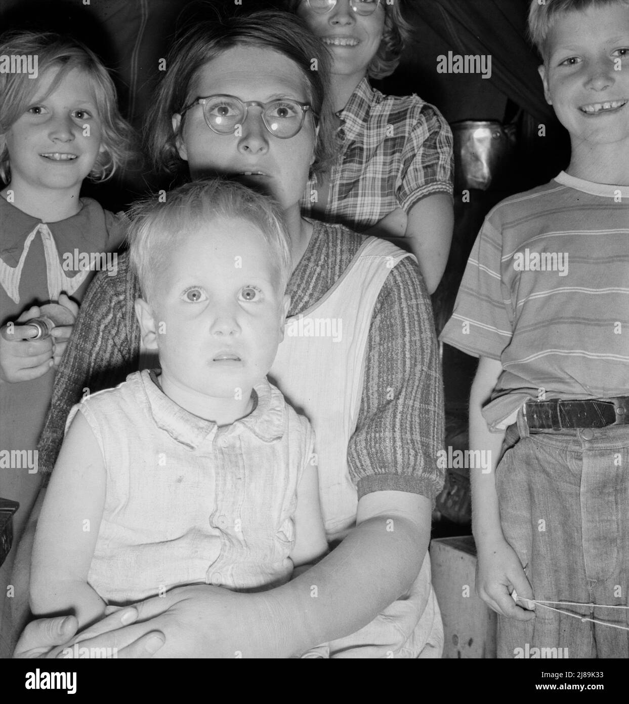 Family of six in tent after supper. Came to potato harvest after father was laid off of WPA (Work Projects Administration) in Boise, Idaho. Oldest child is twelve. Little boy has dysentery. Merrill, Klamath County, Oregon. In FSA (Farm Security Administration) mobile unit. Stock Photo