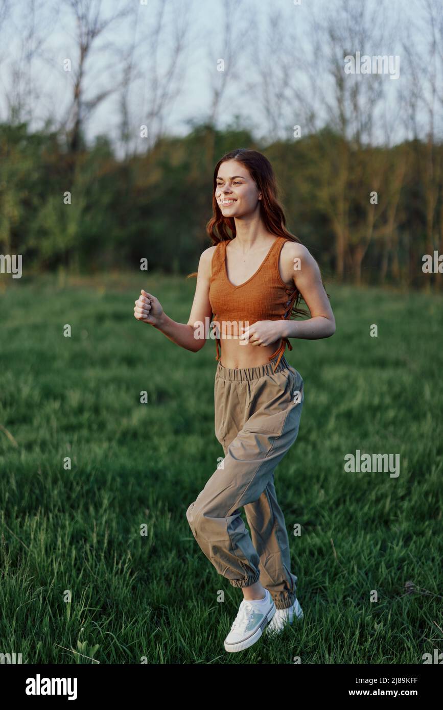 A woman of athletic build runs through the park on the green grass with