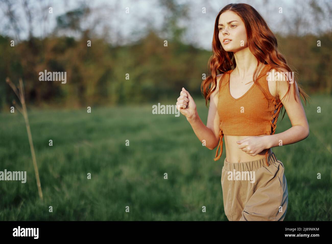 A woman is jogging with a focused face, tired after an outdoor activity