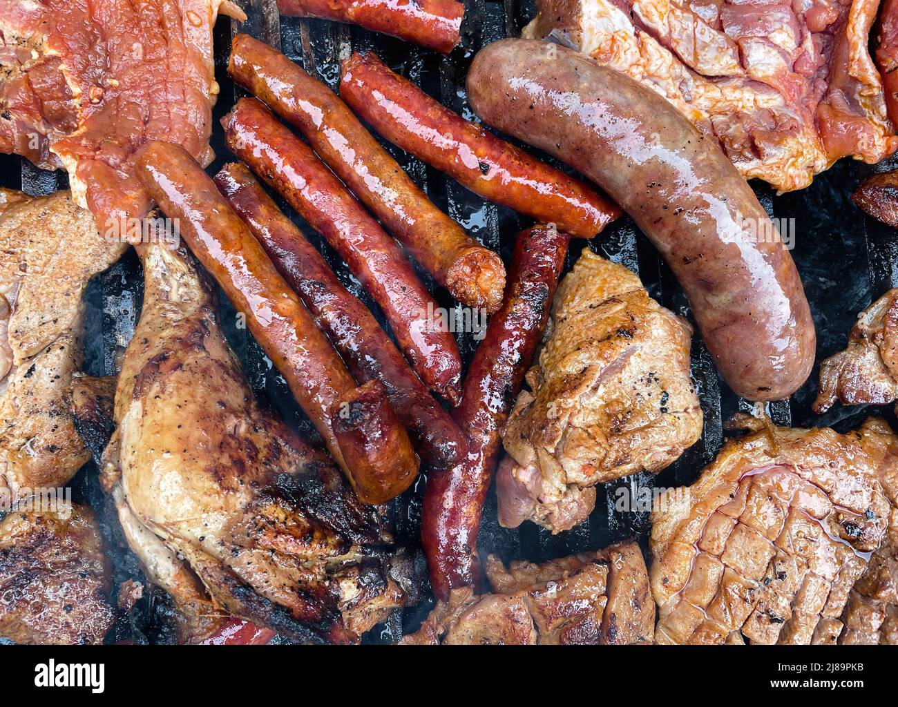 Marinated meat on charcoal grill bbq grilling chicken sausage and pork Stock Photo