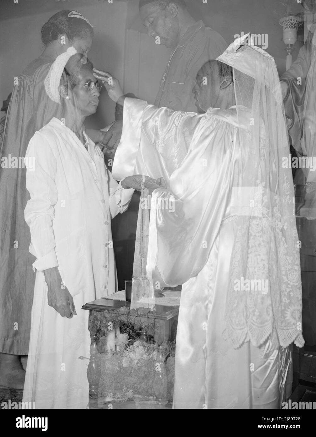 Washington, D.C. Mrs. Ella Watson, a government charwoman, receiving annointment from Reverend Clara Smith during the &quot;flower bowl demonstration,&quot; a service held once a year at the St. Martin's Spiritual Church. Reverend Vondell Gassaway is the pastor. Stock Photo