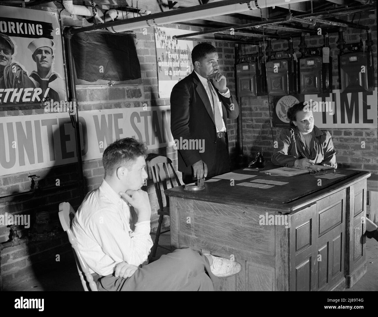 Washington, D.C. Air raid wardens' meeting in zone nine, Southwest area. Mr. Douglas Frederick, who is a firewatcher at the hotel where he is employed and a deputy warden in his neighborhood, listening to a complaint. Stock Photo