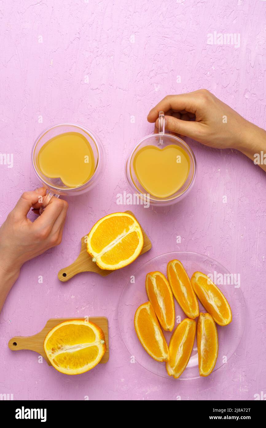 Fresh orange juice in glass and oranges on a pink colored background. Top view, vertical photo. Copy space Stock Photo