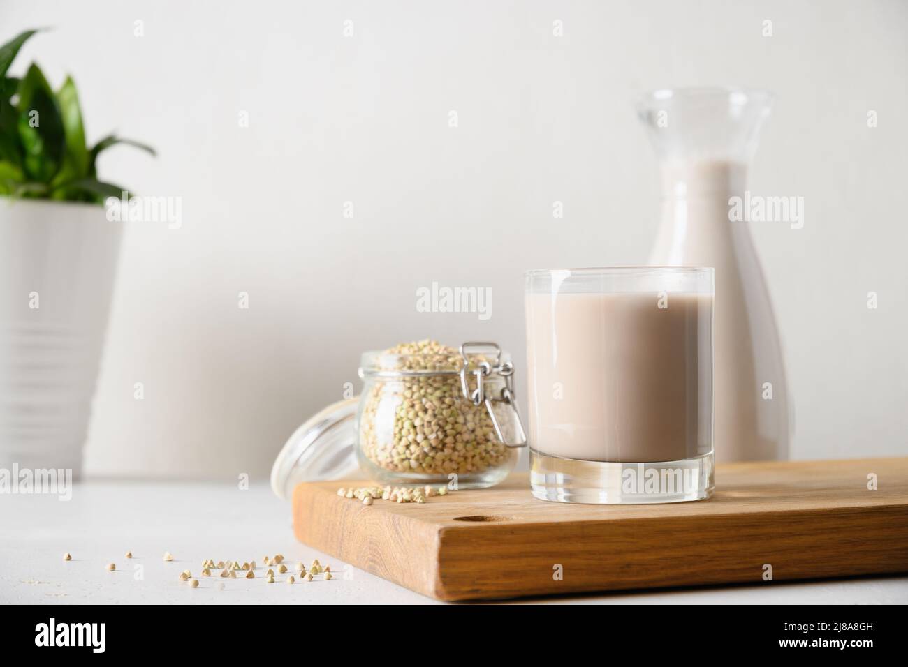 Vegan cereal green buckwheat milk in glass in white kitchen. Plant