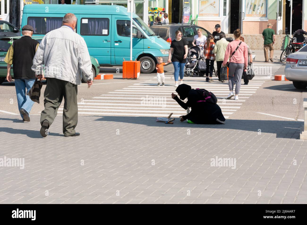 Tiraspol, Moldova - May 13, 2022: A beggar woman begs near the park, kneels and prays. Social problems in the countries of the former USSR, the unreco Stock Photo