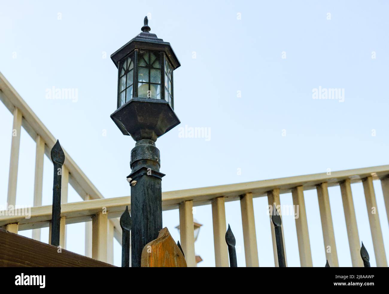 An old-fashioned street lamp on a metal fence. Summer day. Stock Photo