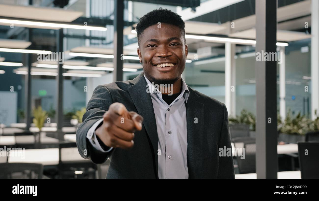 Multiracial man American male businessman investor financial specialist of large company standing with smile pointing index finger at camera with hey Stock Photo