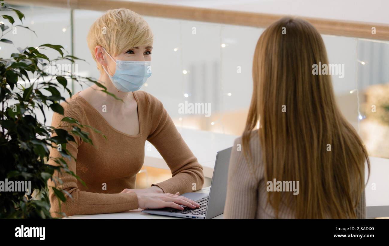 Middle aged business woman consultant bank worker employer manager insurance service female in medical mask consulting client girl hiring job Stock Photo