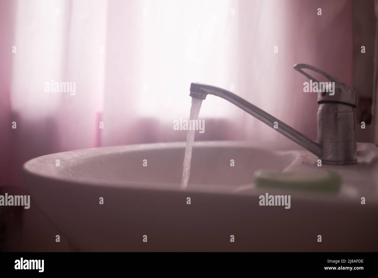 faucet with flowing water in wash sink. Somebody to turn off