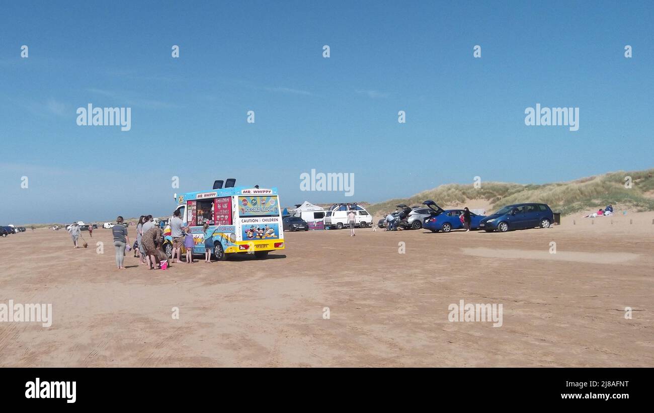 People queuing at an Mr Whippy Ice cream van on the beach, Ainsdale beach, England. Holidays on the beach concept Stock Photo