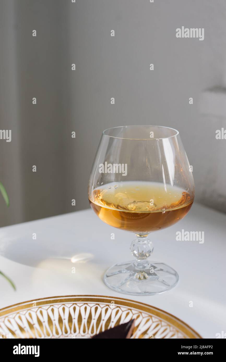 brandy snifter on white reflective table with white background by window Stock Photo