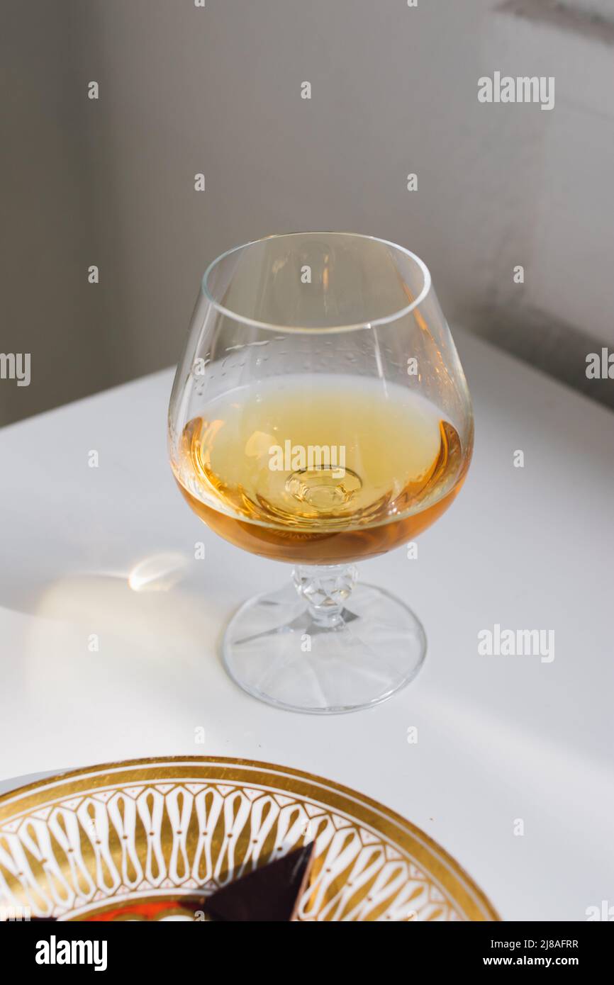 brandy snifter on white reflective table with white background by window Stock Photo