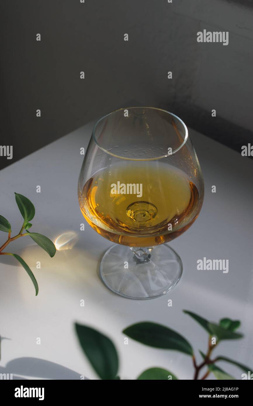 whiskey in brandy snifter on white table Stock Photo