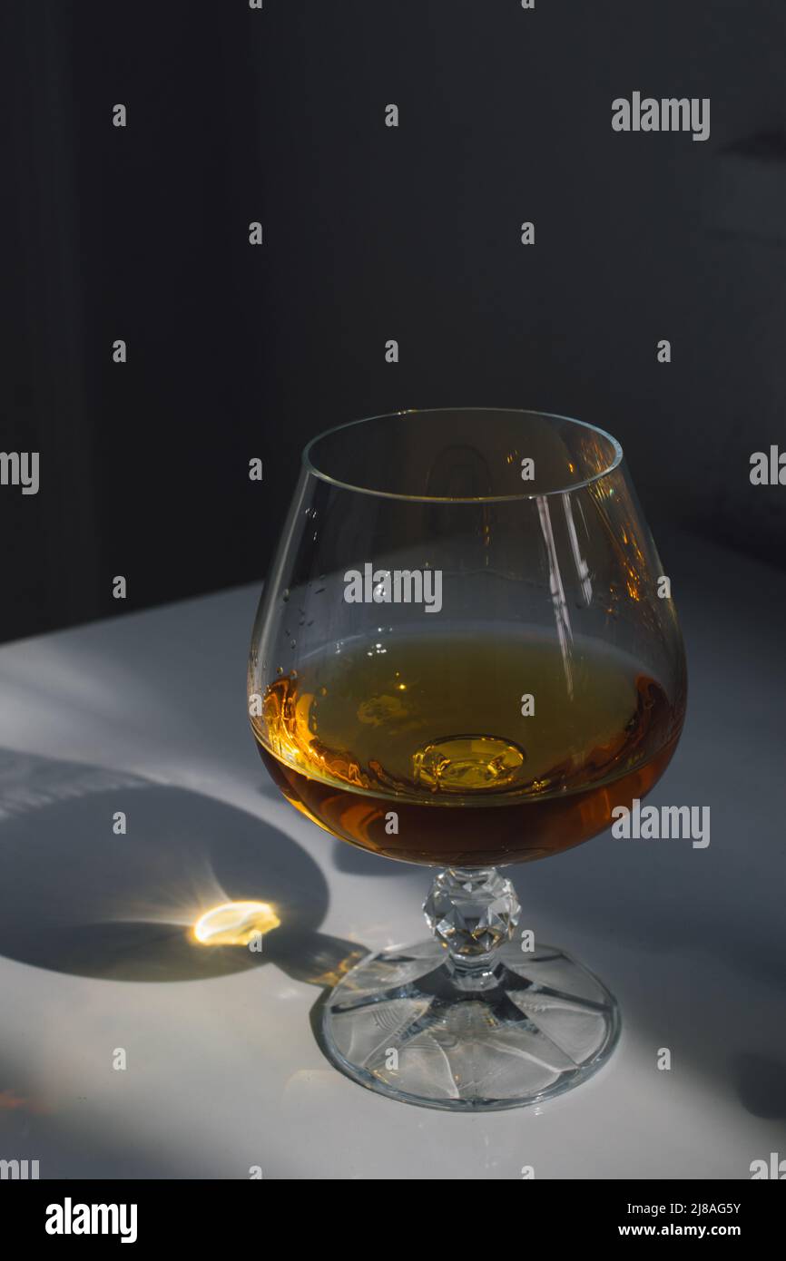 whiskey in brandy snifter on white table Stock Photo