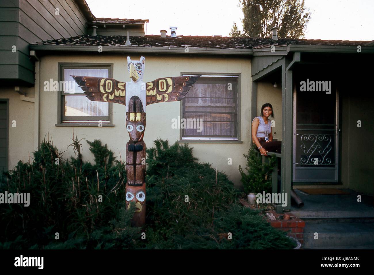 Oakland, Calif. - Urban Indian at home in 1972. Family put a totum pole in front of their home. Totum pole from tribes in northwest United States. Government promoted Native Americans to leave the reservation and move to the cities in the late 1950's and led to occupatin of Alcatraz Island in 1968-1970. Made the Bay Area Native Americans unit and committed to preserving heritage. Stock Photo