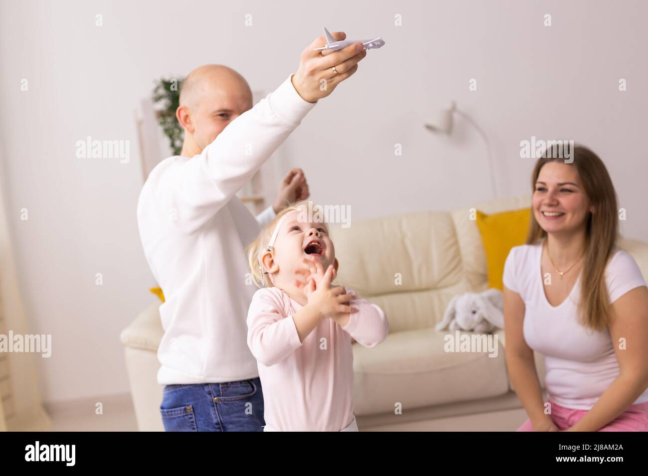Happy child girl with cochlear implant having fun with her family - hearing aid for deaf and innovative health technology concept Stock Photo
