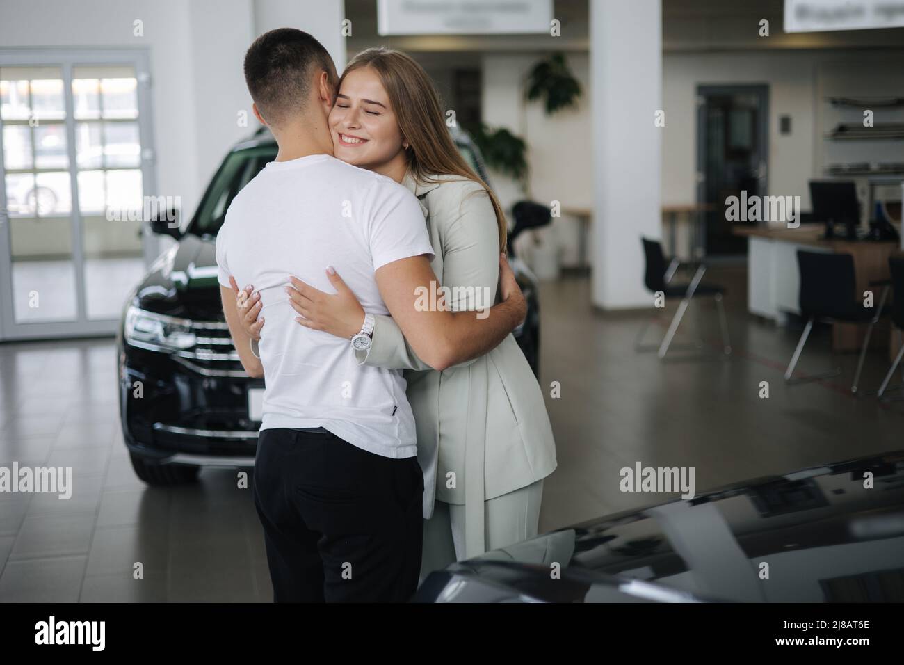 Gorgeous woman hug his husband after buying car in car showroom. Man ...