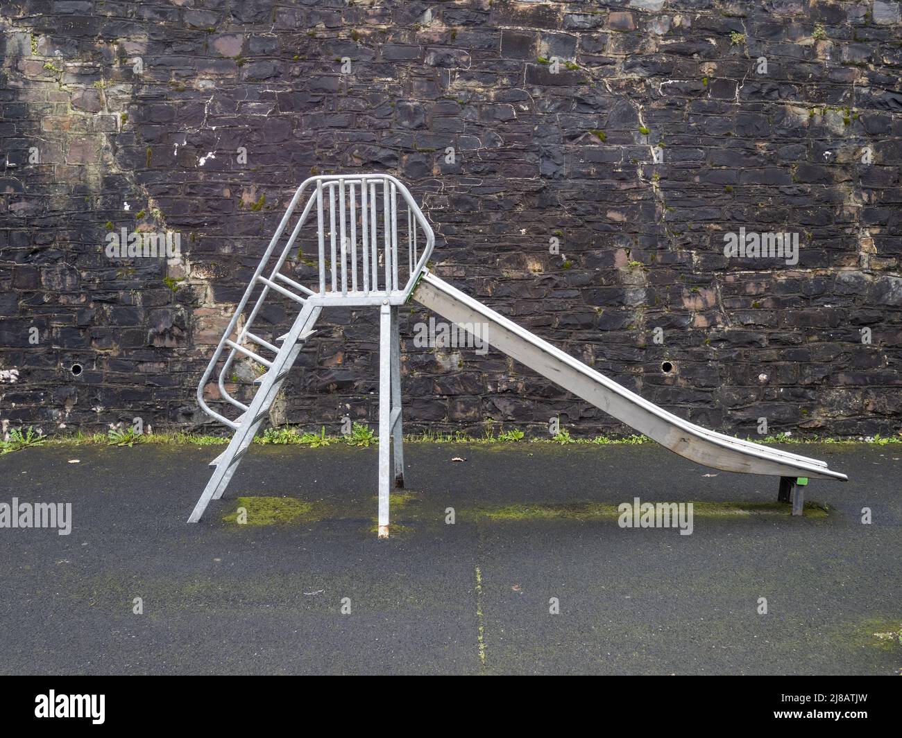 Old fashioned childrens slide, metal. Outdoor play area. No people. Stock Photo