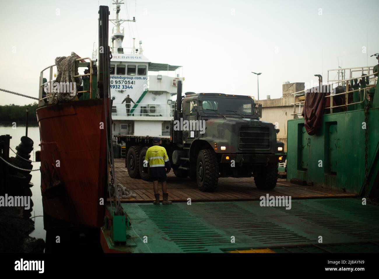 A U.S. Marine with the Logistics Command Element, Marine Rotational Force-Darwin (MRF-D) 22, loads a Medium Tactical Vehicle Replacement onto a barge during a combined logistics movement of equipment for exercise Crocodile Response 22 at Darwin, NT, Australia, May 12, 2022. MRF-D 22 and Australian Army equipment was loaded onto civilian barges for transportation, demonstrating the flexibility to conduct humanitarian assistance and disaster relief within different operating environments. (U.S. Marine Corps Photo by Cpl. Cedar Barnes) Stock Photo