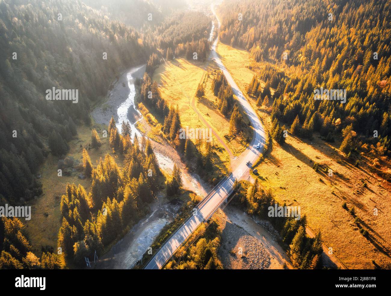 Aerial view of mountain road and beautiful forest at sunset Stock Photo ...