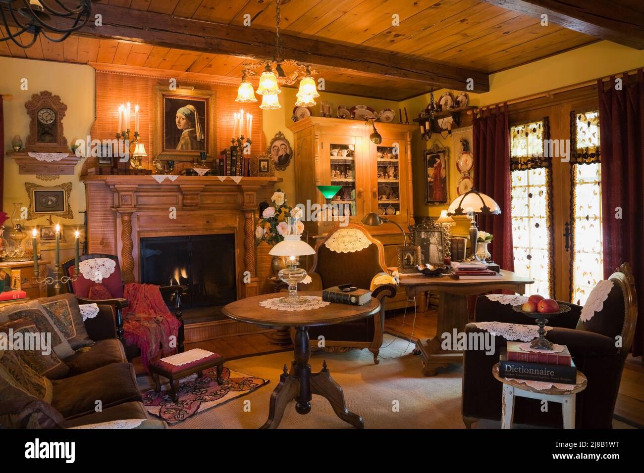 Antique armchairs and furnishings in lavishly decorated living room inside old reconstructed 1800s Canadiana cottage style log home. Stock Photo