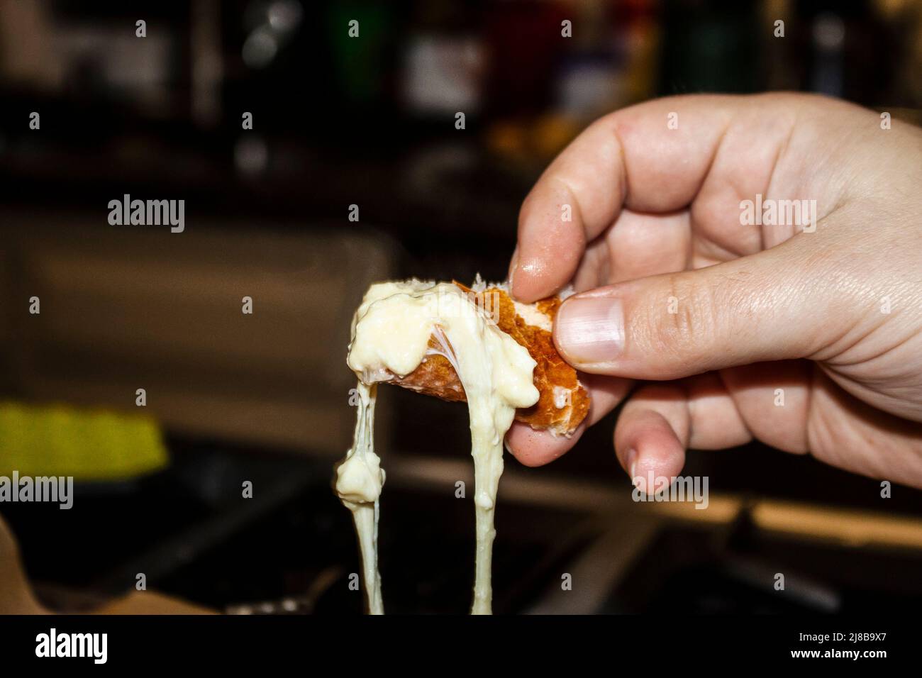 Georgian khachapuri - hand holding a piece of the bread torn off the bowl dripping with melted cheese Stock Photo