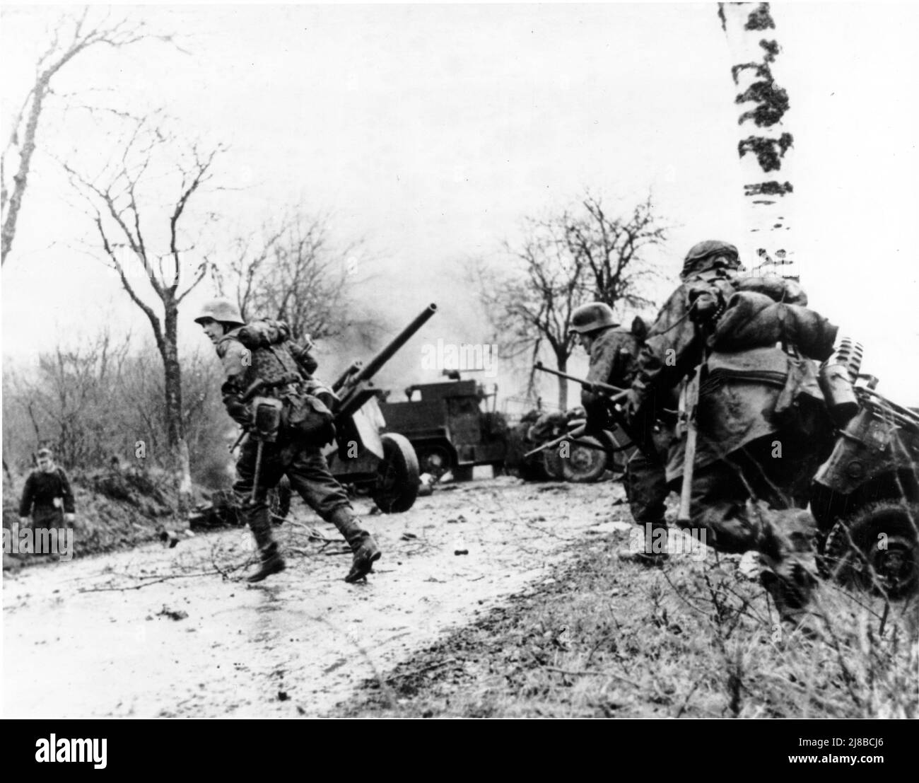German troops advancing past abandoned American equipment during the Battle of the Bulge. Stock Photo