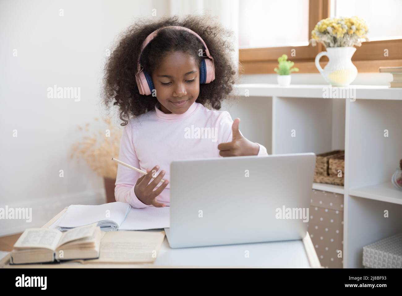 African girl in headphones looks at laptop show thumbs up Stock Photo