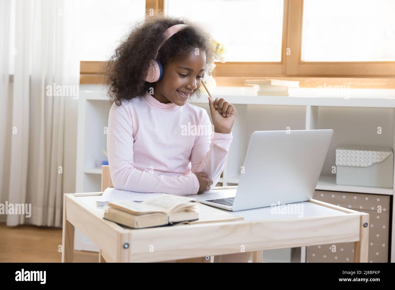 Little African girl in headphones using laptop studying at home Stock ...