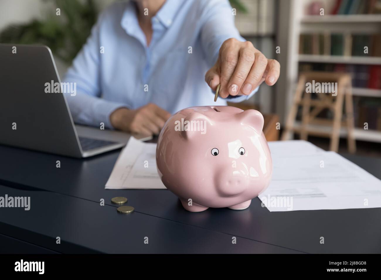 Mature business woman inserting cash into piggy bank Stock Photo - Alamy