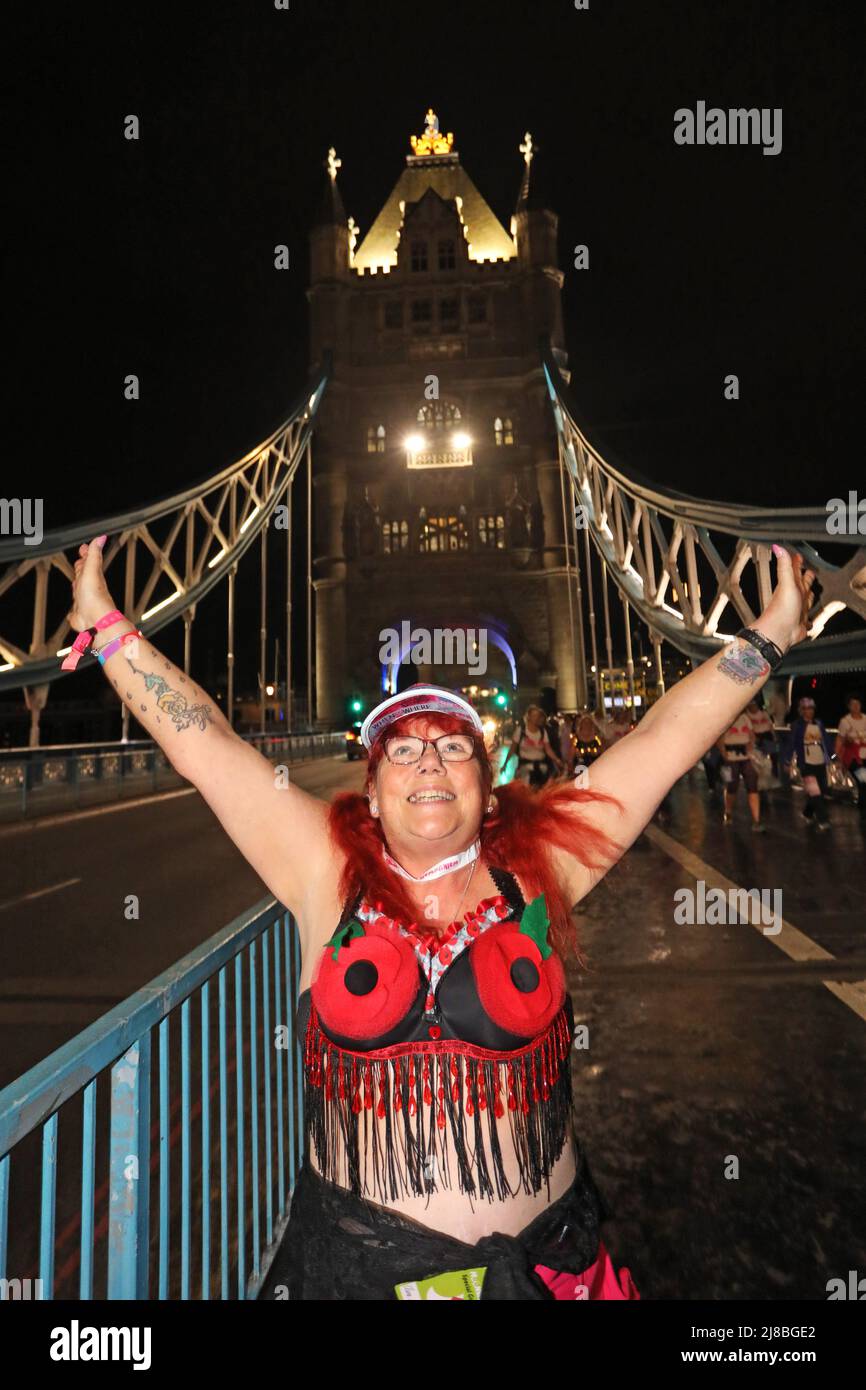 London, UK. 14th May 2022. London, UK. Participant with Poppy Bra on Tower Bridge at the Walk the Walk Moonwalk walking through London wearing decorated bras fundraising for breast cancer charities doing a marathon overnight. This year the theme is 'Your Heroes' and there were numerous rainbow themed costumes and bras in support of NHS heroes, also many superhero costumes and even blue and yellow Ukranian flag themed costumes in support of Ukrainian heroes. Credit: Paul Brown/Alamy Live News Stock Photo
