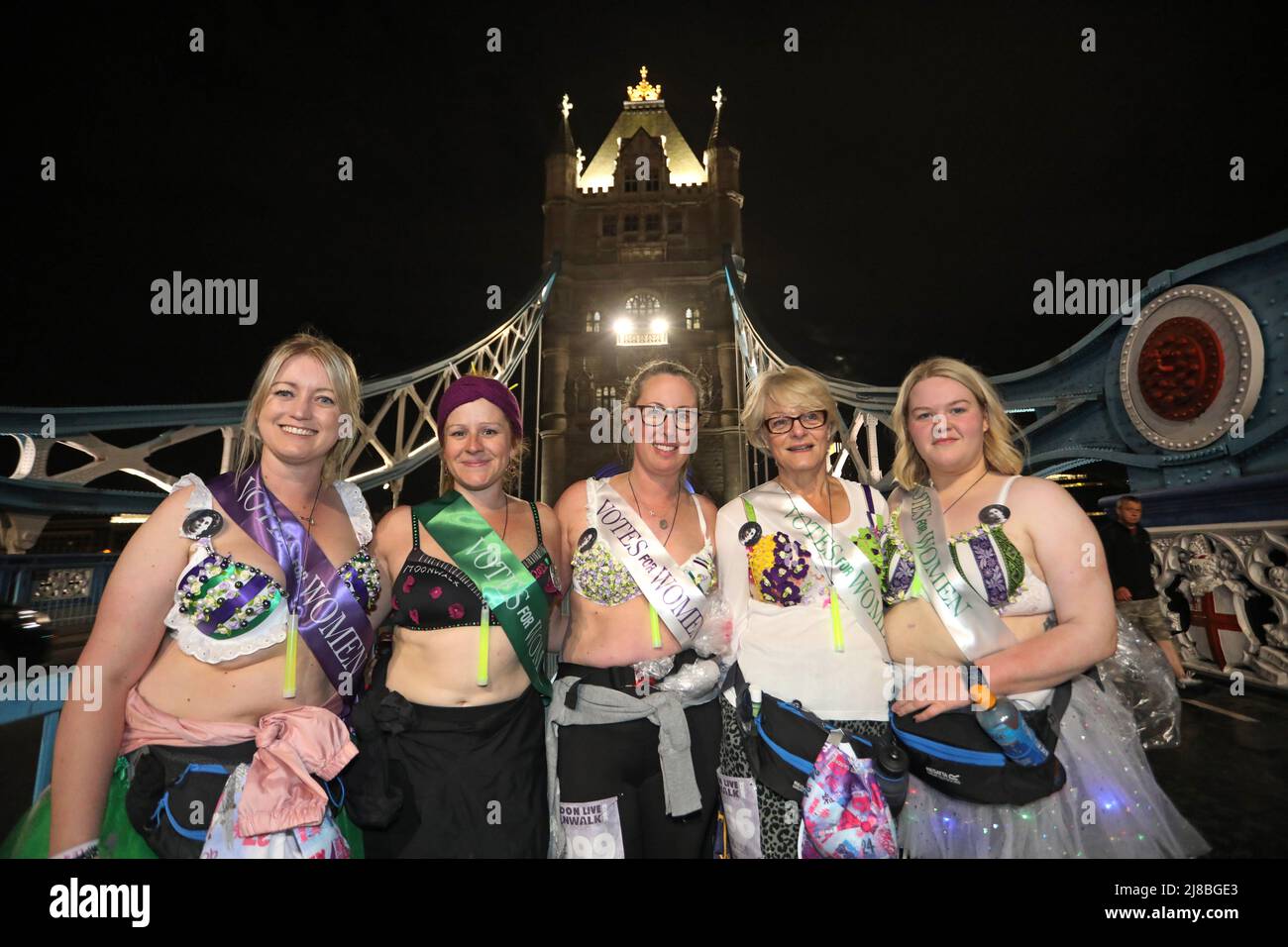London, UK. 14th May 2022. London, UK. Participants honouring their suffragette heroes by wearing Votes for Women costumes on Tower Bridge at the Walk the Walk Moonwalk walking through London wearing decorated bras fundraising for breast cancer charities doing a marathon overnight. This year the theme is 'Your Heroes' and there were numerous rainbow themed costumes and bras in support of NHS heroes, also many superhero costumes and even blue and yellow Ukranian flag themed costumes in support of Ukrainian heroes. Credit: Paul Brown/Alamy Live News Stock Photo