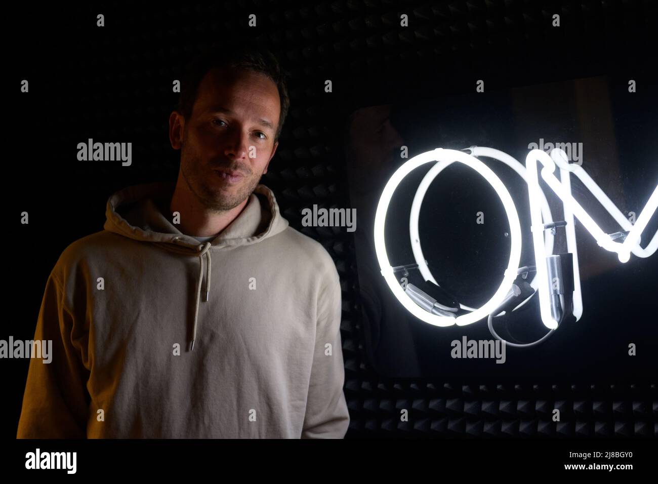 26 April 2022, Hamburg: OMR boss Philipp Westermeyer stands next to an OMR logo in his podcast studio. (to dpa: OMR in Hamburg - Digital trade fair with star-studded line-up and good music) Photo: Jonas Walzberg/dpa Stock Photo