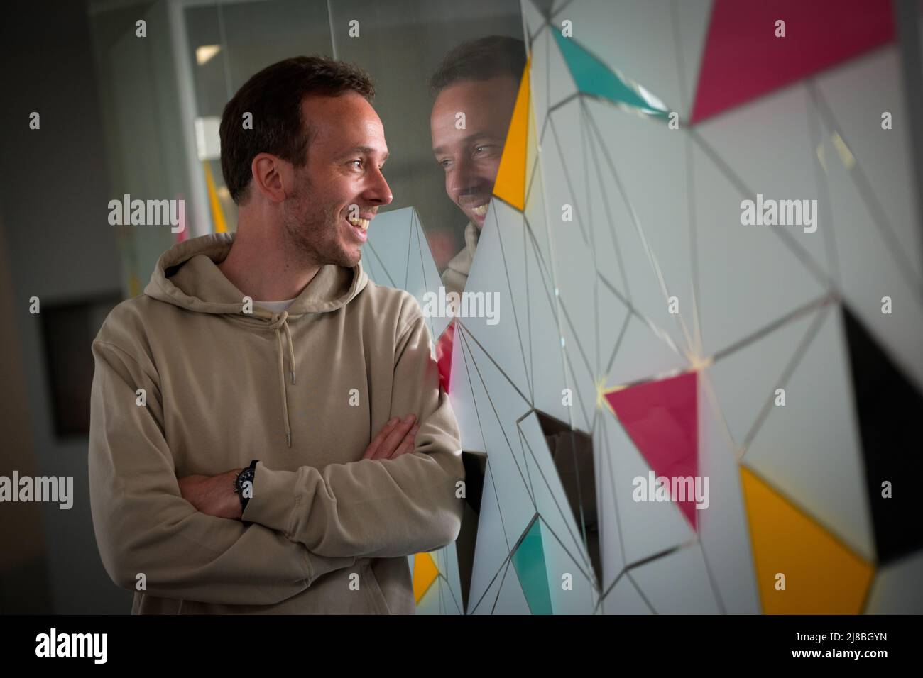 26 April 2022, Hamburg: OMR CEO Philipp Westermeyer looks through a pane of glass into an office room, smiling. (to dpa: OMR in Hamburg - Digital trade fair with star-studded crowd and good music) Photo: Jonas Walzberg/dpa Stock Photo