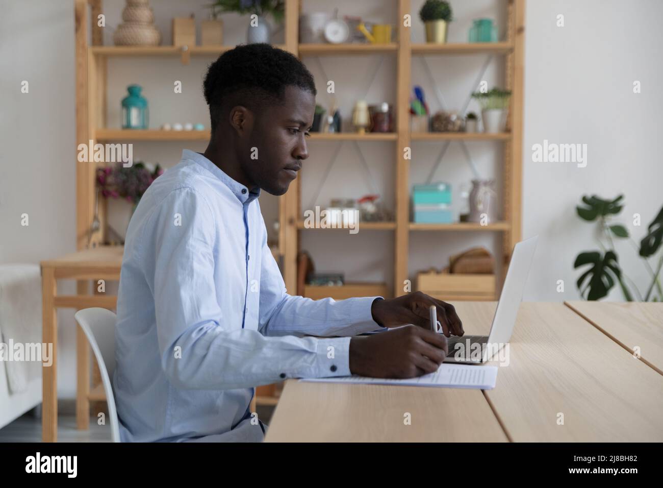 Focused Black student guy watching learning webinar on laptop Stock Photo