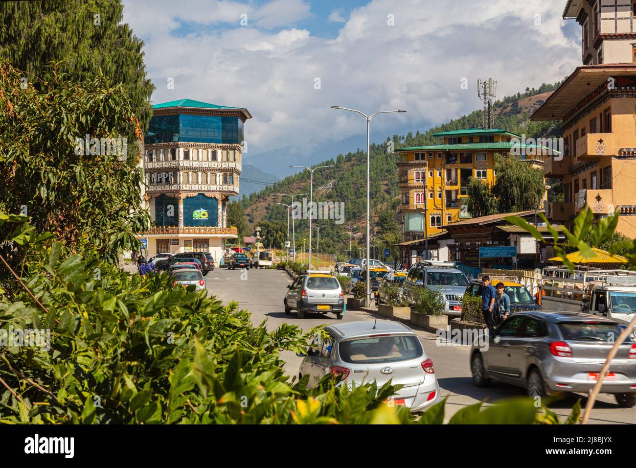 Thimphu, Bhutan - October 28, 2021: Street view Thimphu. Traditional architecture in the Bhutanese city. Cars driving on the street and people crossin Stock Photo