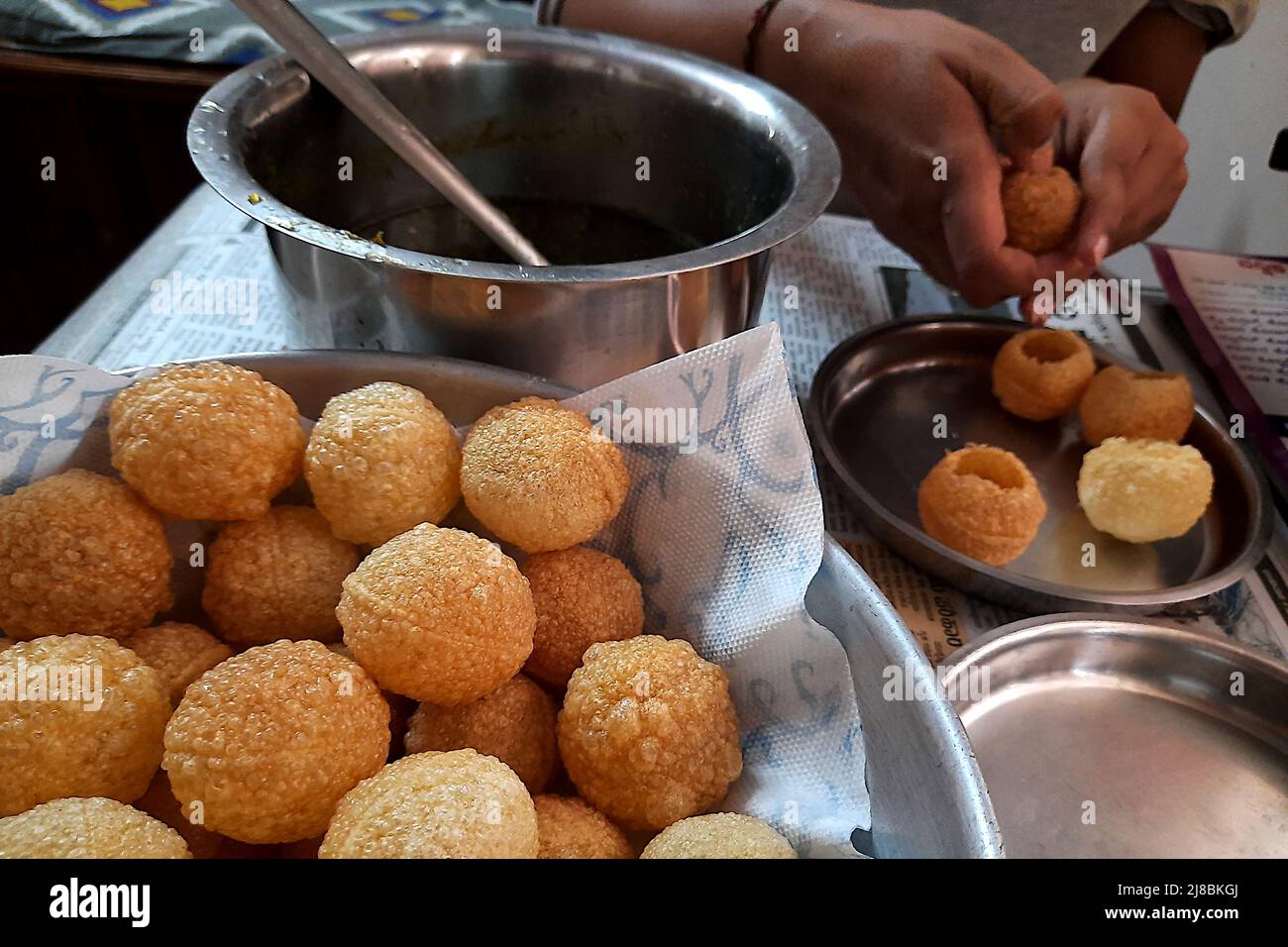 Image showing filling spiced pani in hollow puri balls of Pani-Puri dish Stock Photo