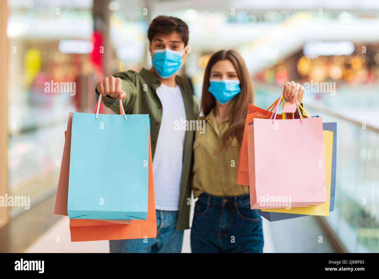 Couple Shopping Showing Shopper Bags Posing Wearing Masks In Mall Stock