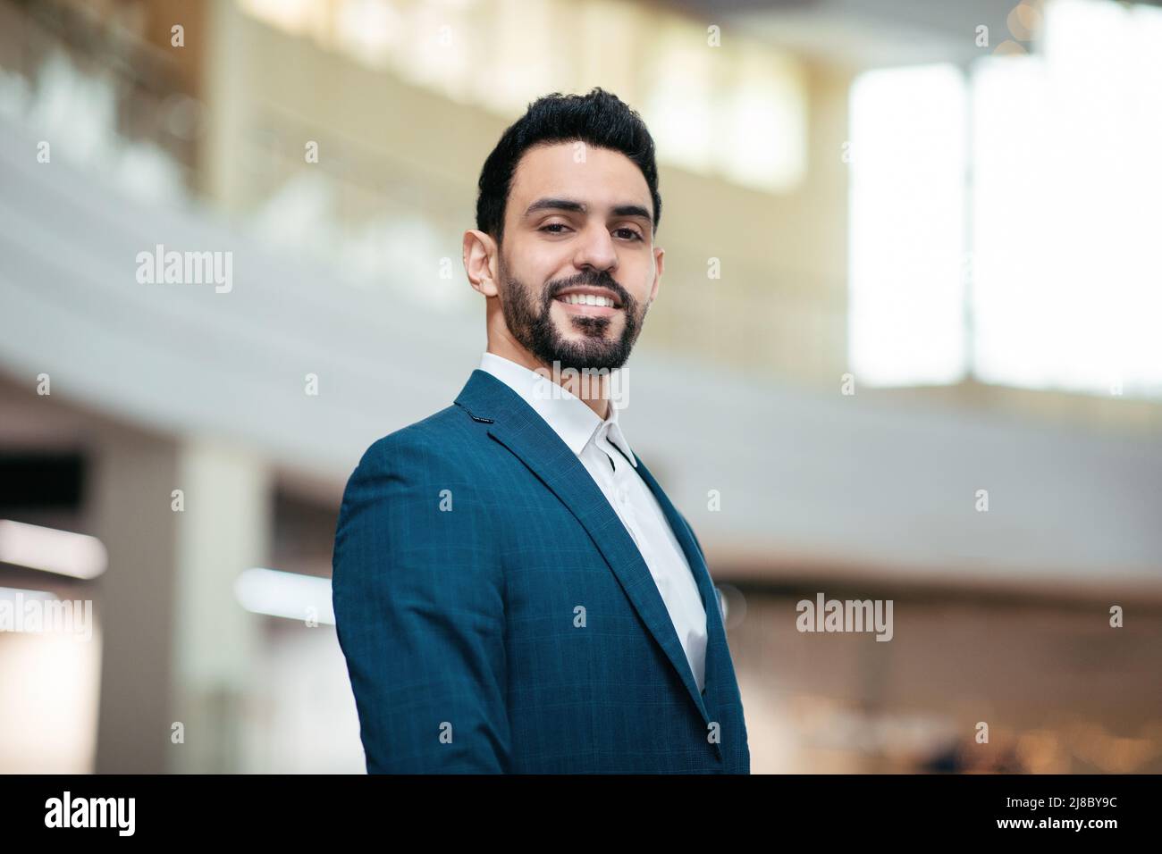Smiling confident attractive young arab guy, general manager with beard in suit looks at camera Stock Photo