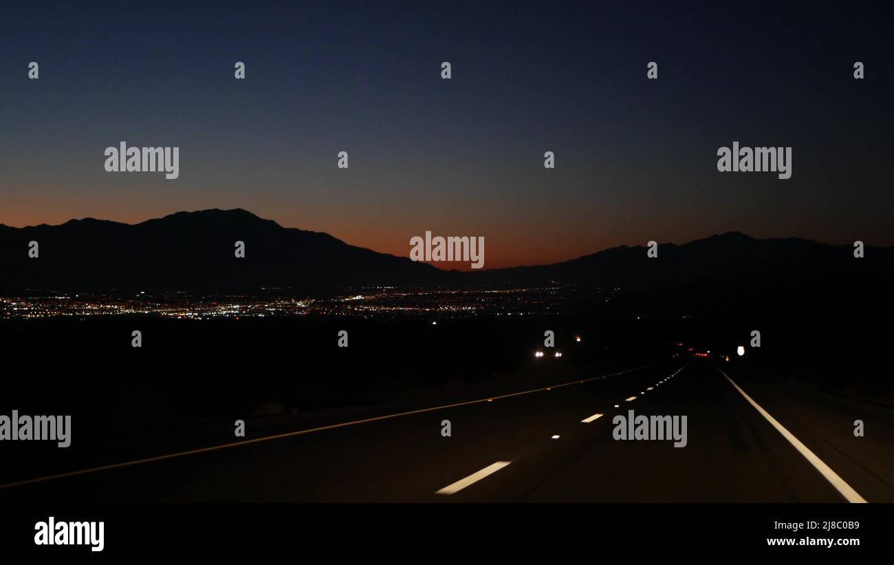 Car driving on desert road at night, freeway or highway in twilight