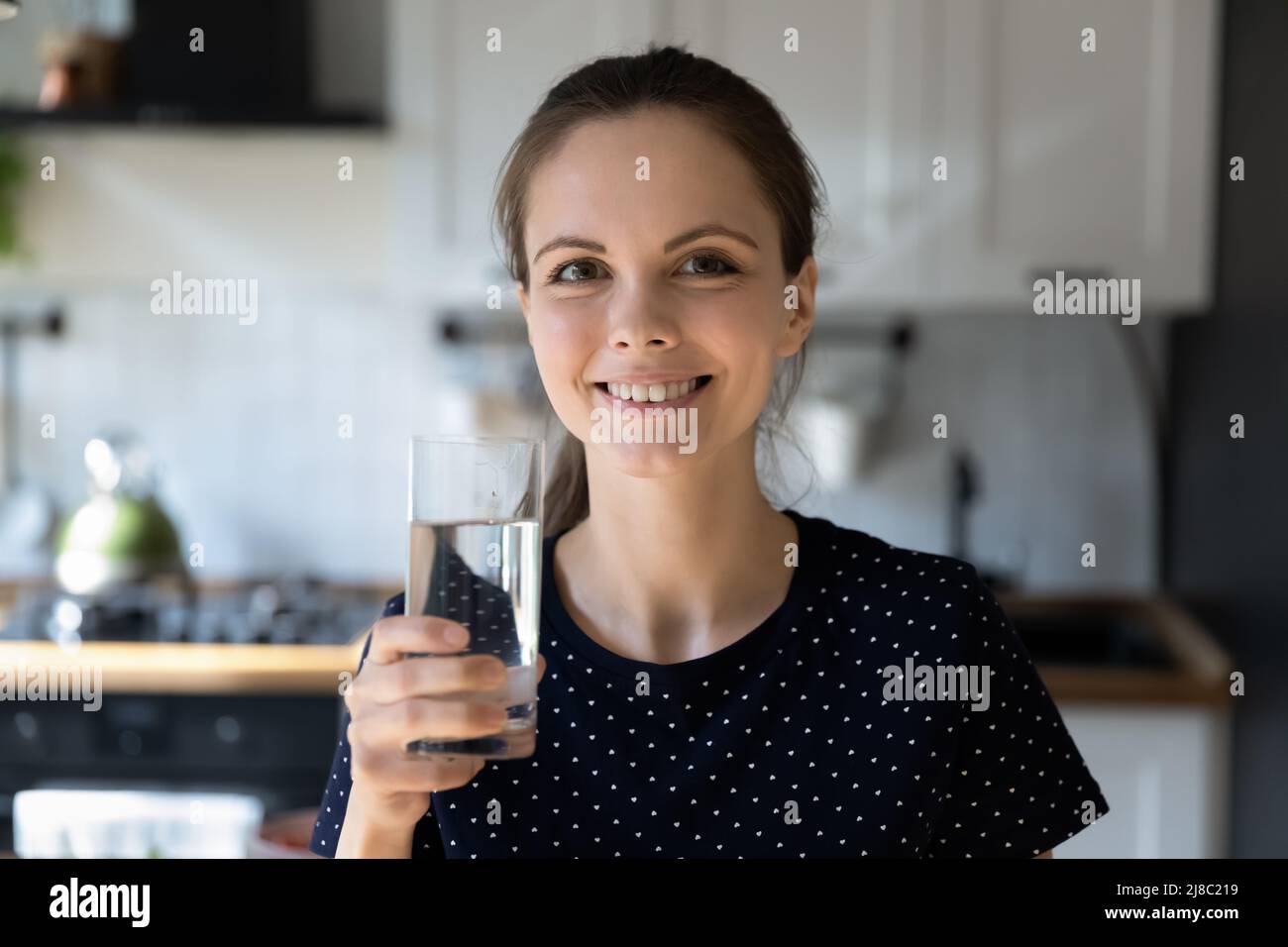 Happy woman drinking fresh pure mineral water in kitchen Stock Photo