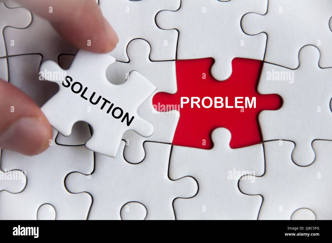 Solution and problem text on jigsaw with one hand holding a missing