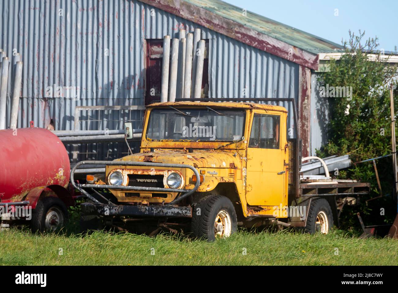 Yellow Toyota Land Cruiser J40 outside barn near Waverly, South Taranaki, North Island, New Zealand Stock Photo