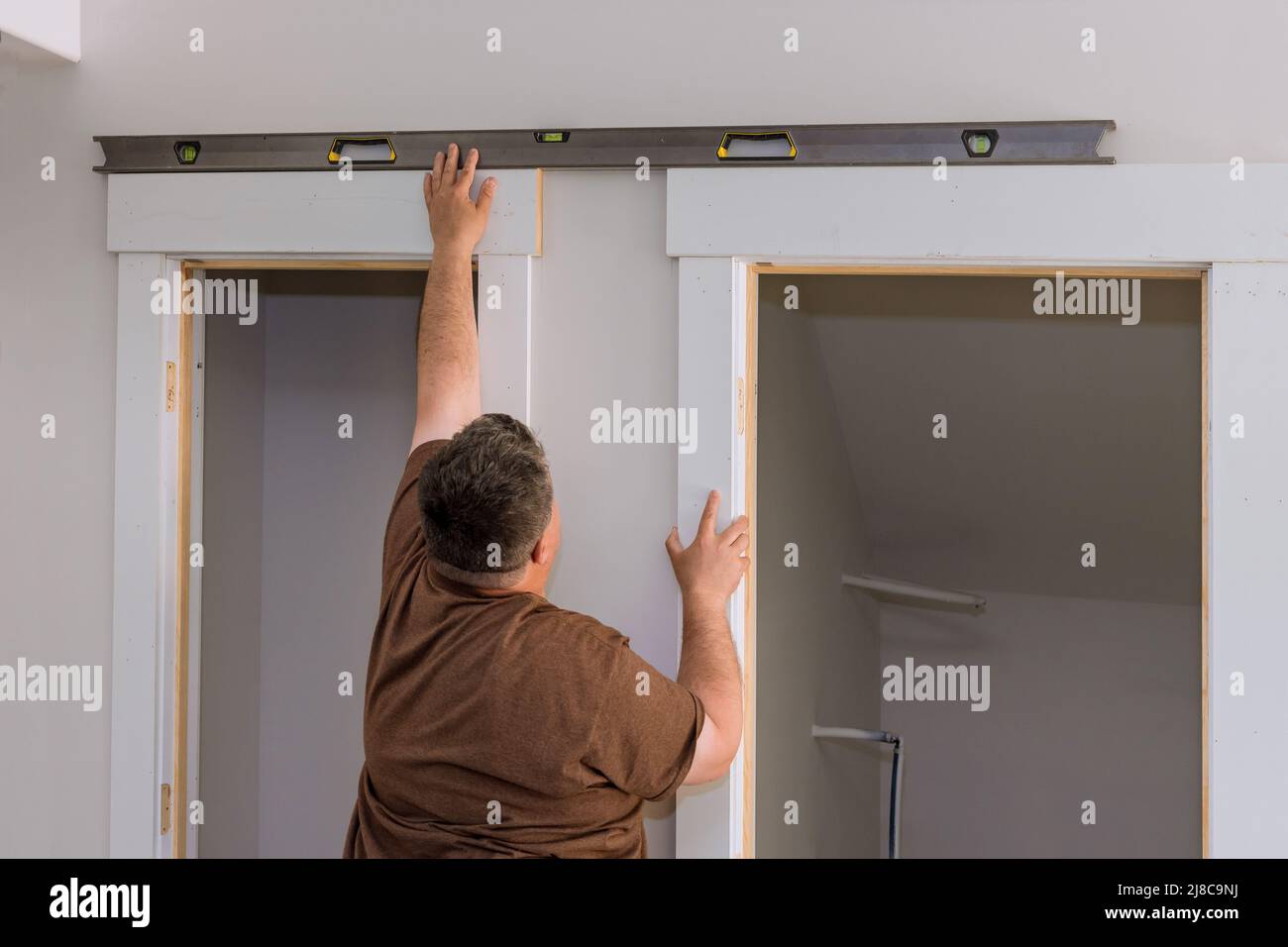 Carpenter at checks level correctness installation door Stock Photo Alamy